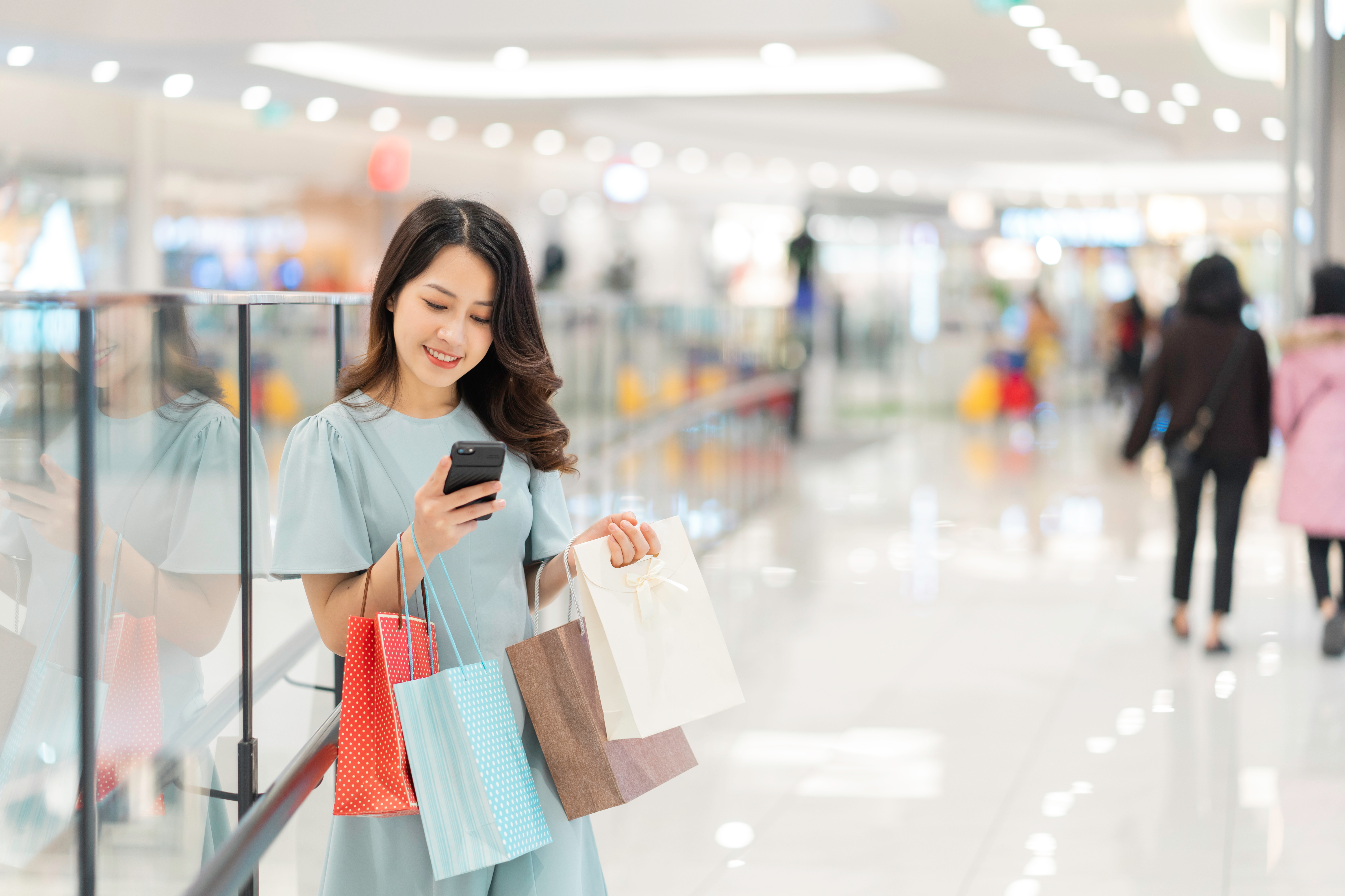 a person holding shopping bags and looking at her phone