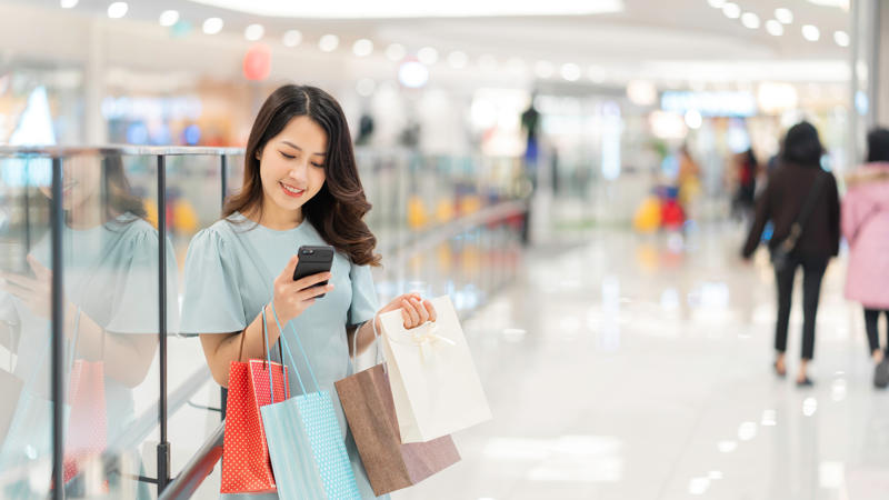 a person holding shopping bags and looking at her phone