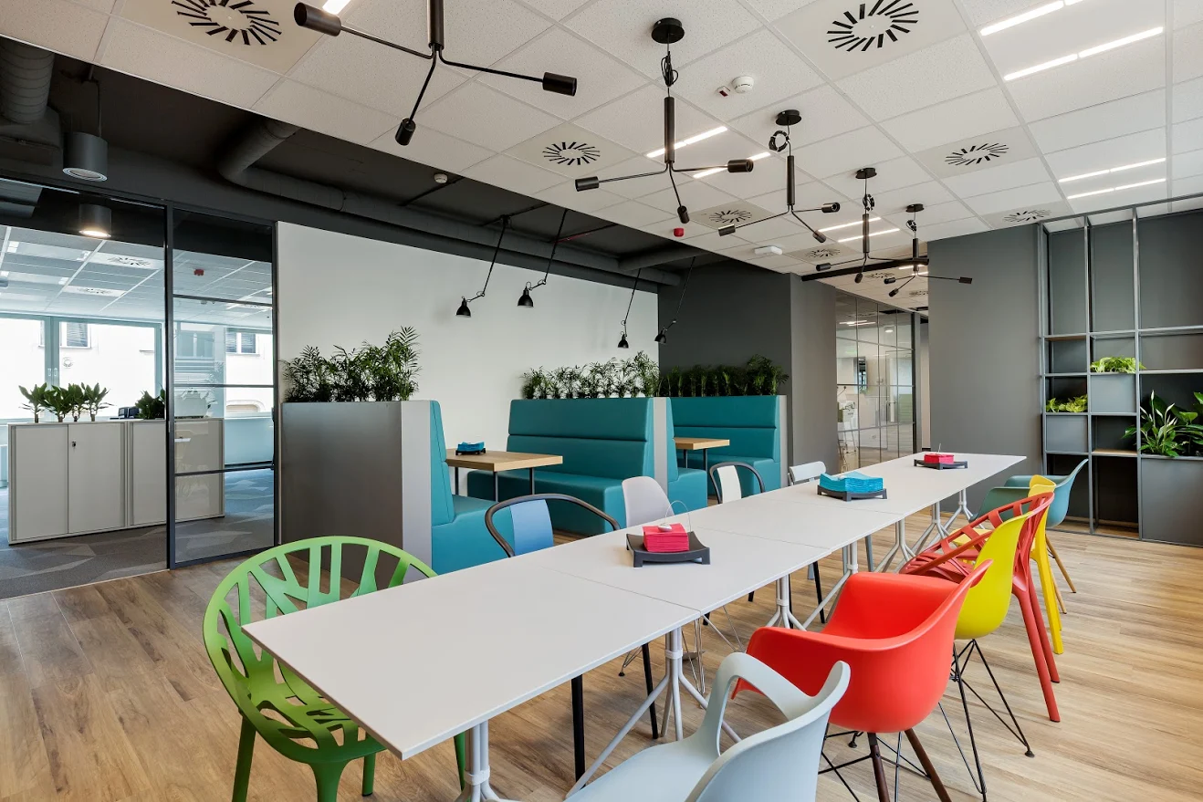 Una sala con mesas blancas y sillas de colores