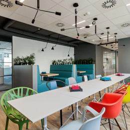 Una sala con mesas blancas y sillas de colores