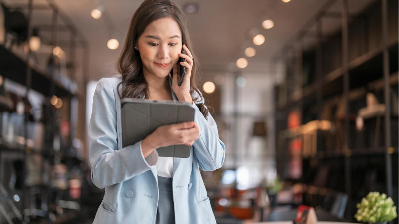 une personne tenant une tablette et parlant au téléphone