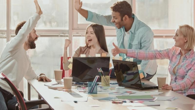 Un grupo de personas en una mesa con computadoras portátiles y una computadora portátil