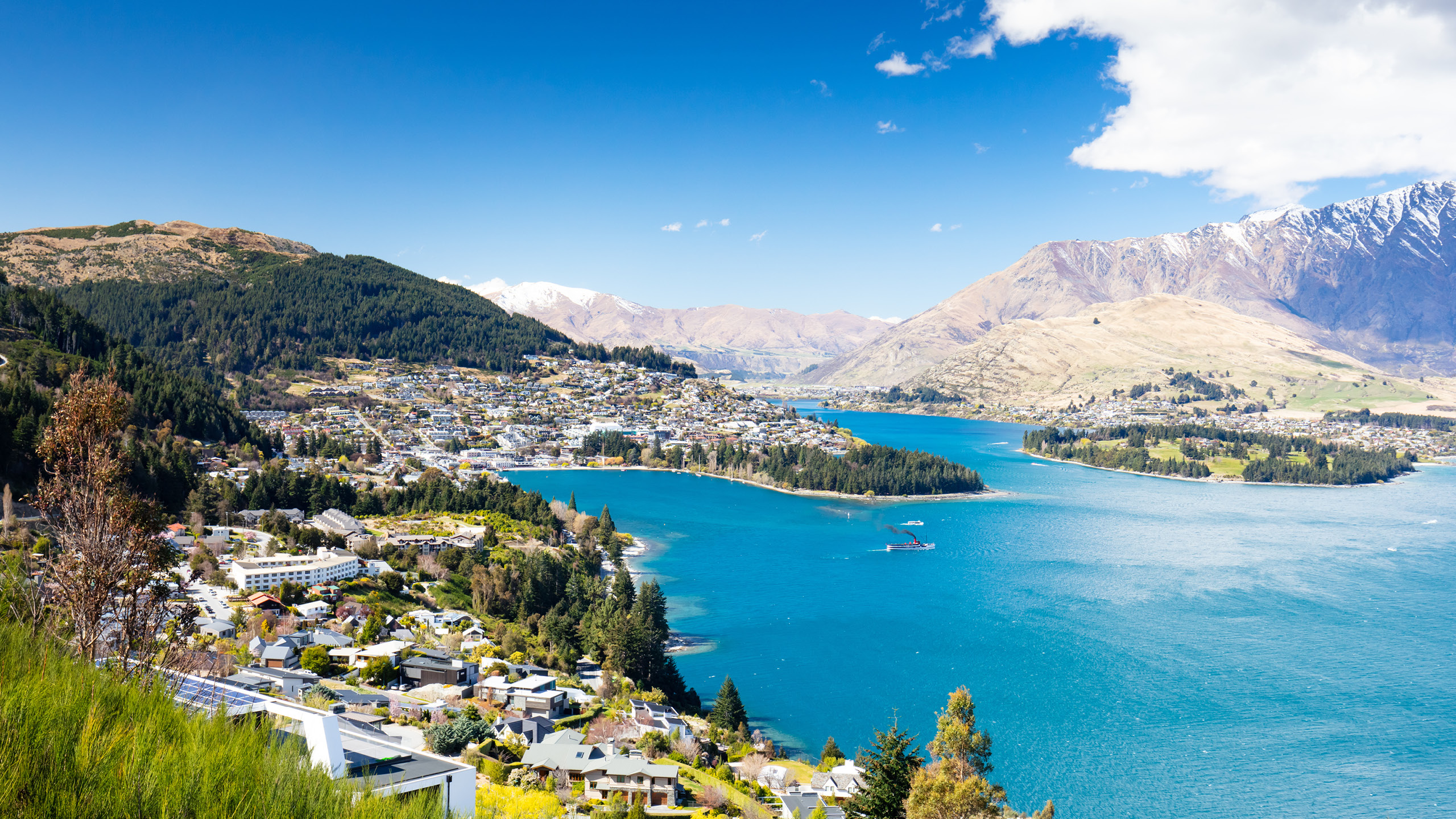 a body of water with buildings and mountains in the background