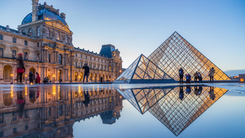 a glass pyramids in front of Louvre