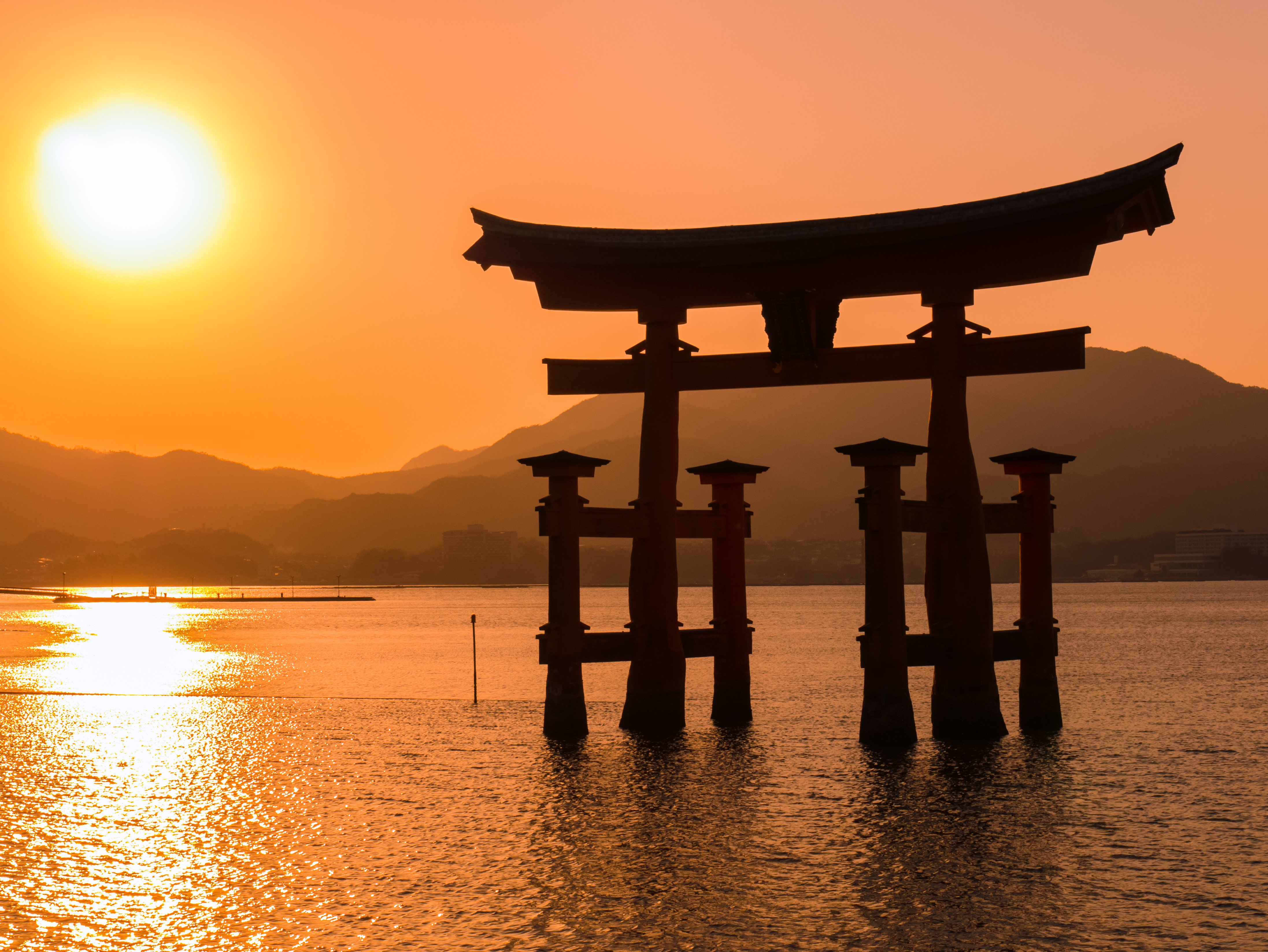 une grande structure dans l’eau avec le sanctuaire d’Itsukushima en arrière-plan