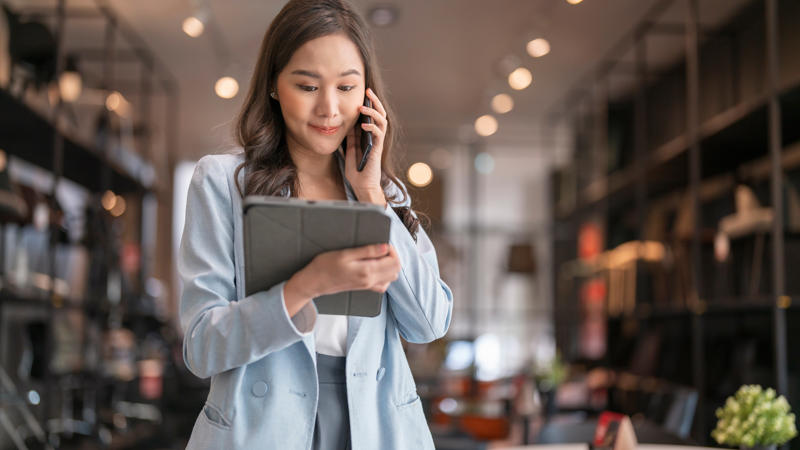 a person holding a tablet and talking on the phone