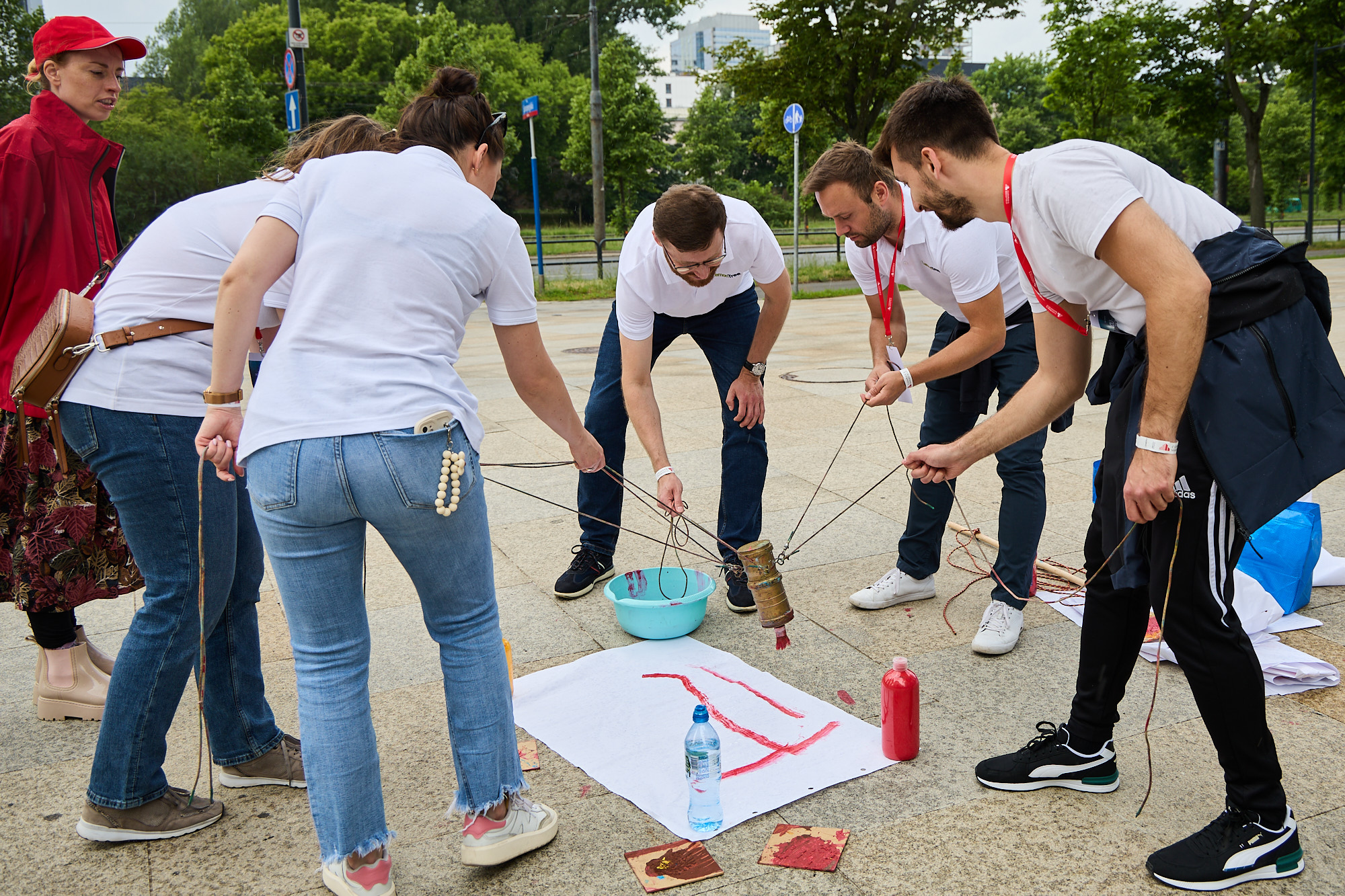 un groupe de personnes à l’extérieur avec une corde attachée à une feuille de papier blanc