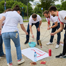 un groupe de personnes à l’extérieur avec une corde attachée à une feuille de papier blanc