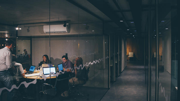 Un grupo de personas sentadas en una mesa con computadoras portátiles