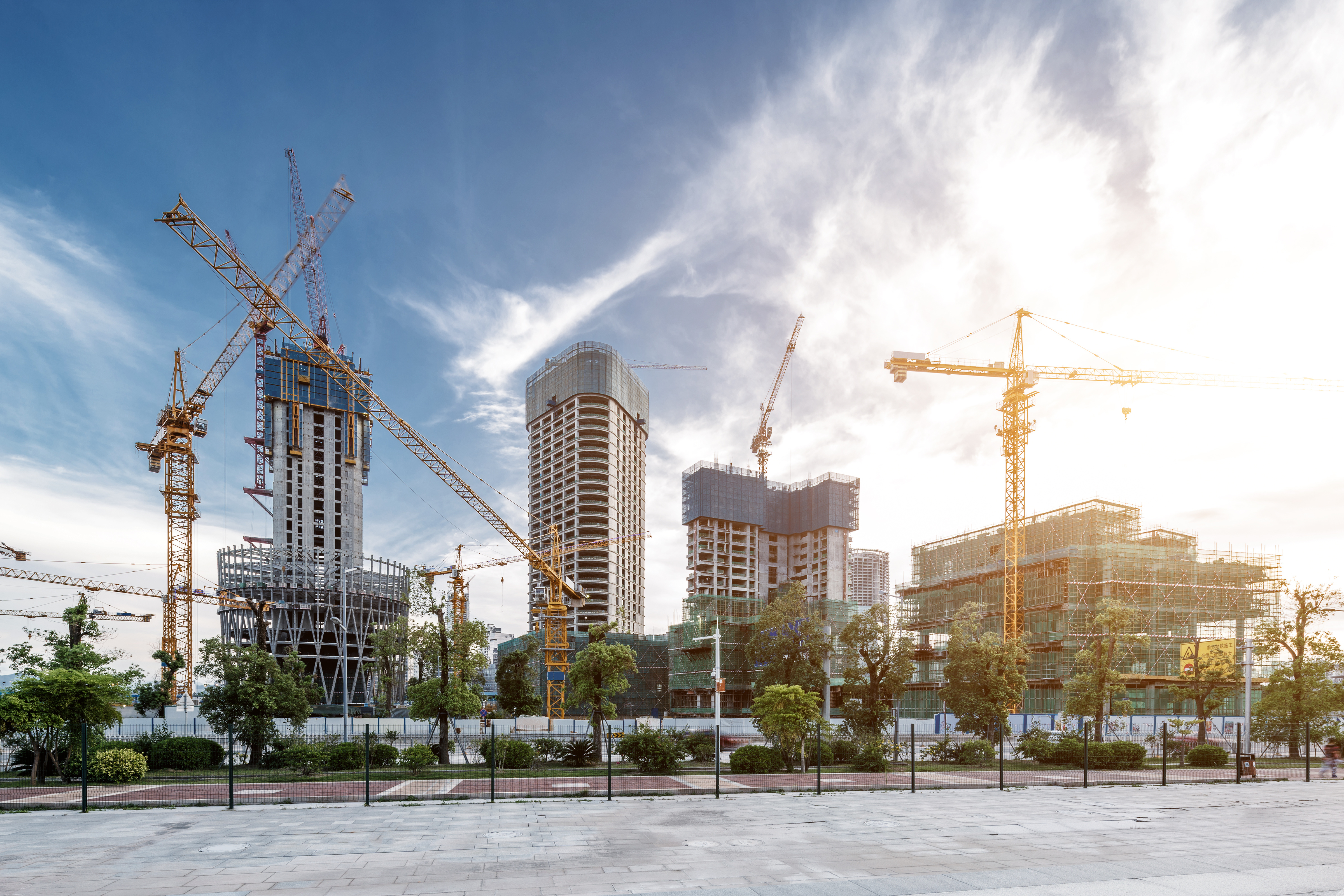 a construction site with cranes and trees