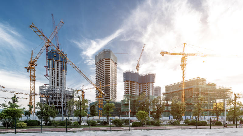 a construction site with cranes and trees