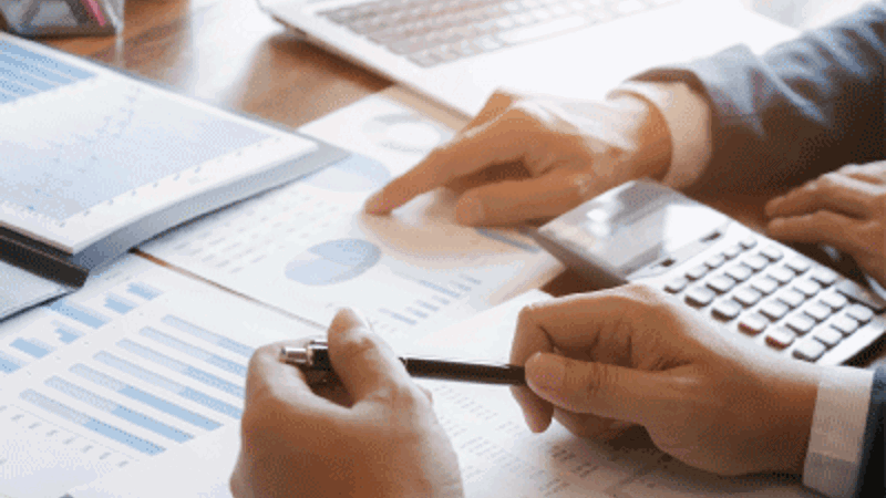 Un primer plano de manos sosteniendo un bolígrafo y señalando un gráfico