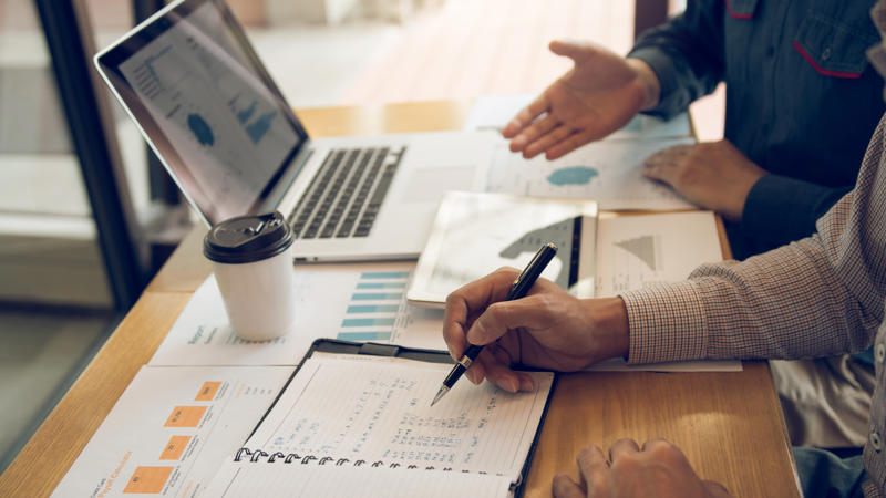 a person holding a pen and writing on a notebook