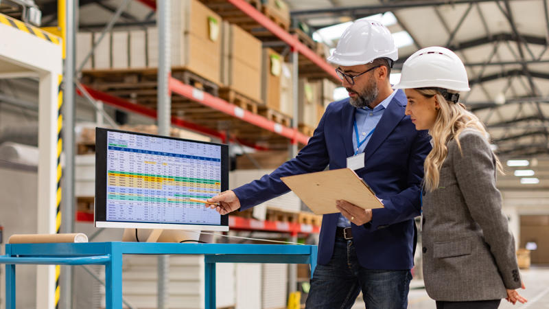 a person and person wearing hardhats looking at a computer screen